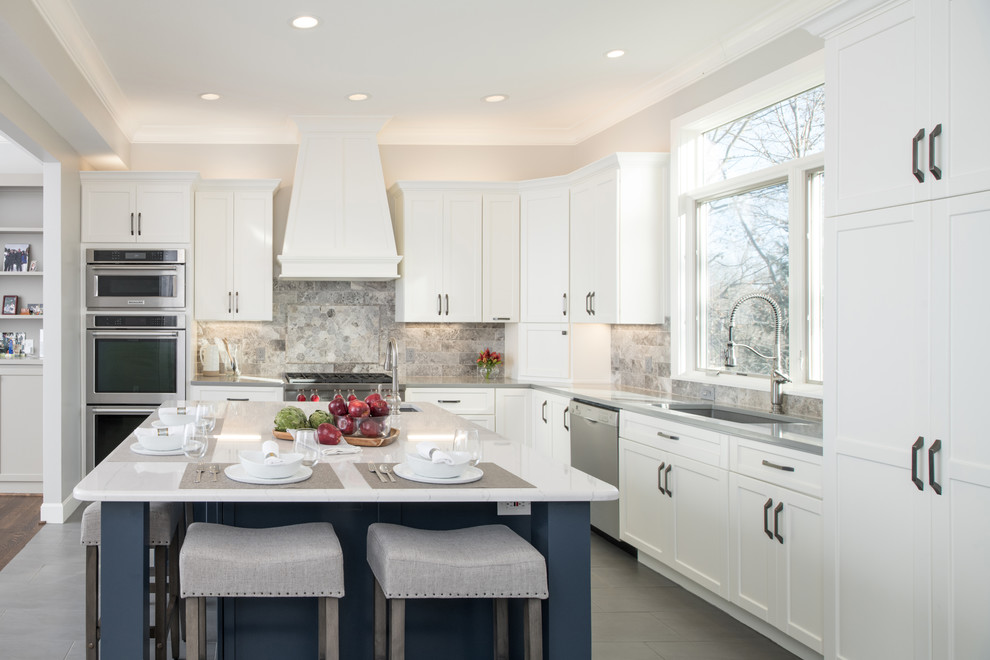 This is an example of a large classic l-shaped kitchen in Kansas City with a single-bowl sink, shaker cabinets, white cabinets, engineered stone countertops, grey splashback, stone tiled splashback, stainless steel appliances, porcelain flooring, grey floors and white worktops.