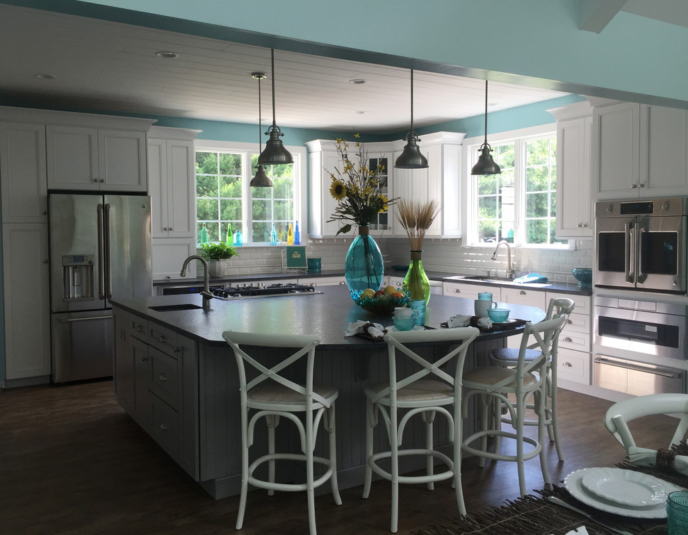 Nautical u-shaped kitchen/diner in Baltimore with a submerged sink, shaker cabinets, white cabinets, white splashback, metro tiled splashback, stainless steel appliances, medium hardwood flooring and an island.