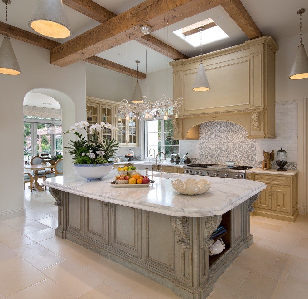 Example of a large tuscan beige floor kitchen design in San Diego with an undermount sink, raised-panel cabinets, distressed cabinets, marble countertops, an island, stainless steel appliances, gray backsplash and stone tile backsplash