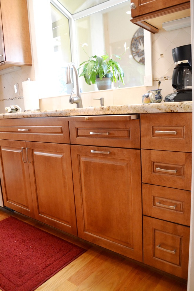 Exempel på ett litet klassiskt kök, med en undermonterad diskho, luckor med upphöjd panel, skåp i mellenmörkt trä, granitbänkskiva, vitt stänkskydd, stänkskydd i porslinskakel, rostfria vitvaror och ljust trägolv