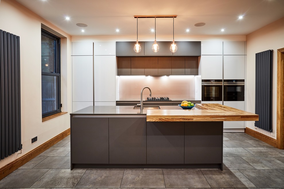 Inspiration for a medium sized modern single-wall kitchen/diner in Other with a built-in sink, flat-panel cabinets, grey cabinets, quartz worktops, metallic splashback, glass sheet splashback, stainless steel appliances, ceramic flooring, an island, grey floors and grey worktops.