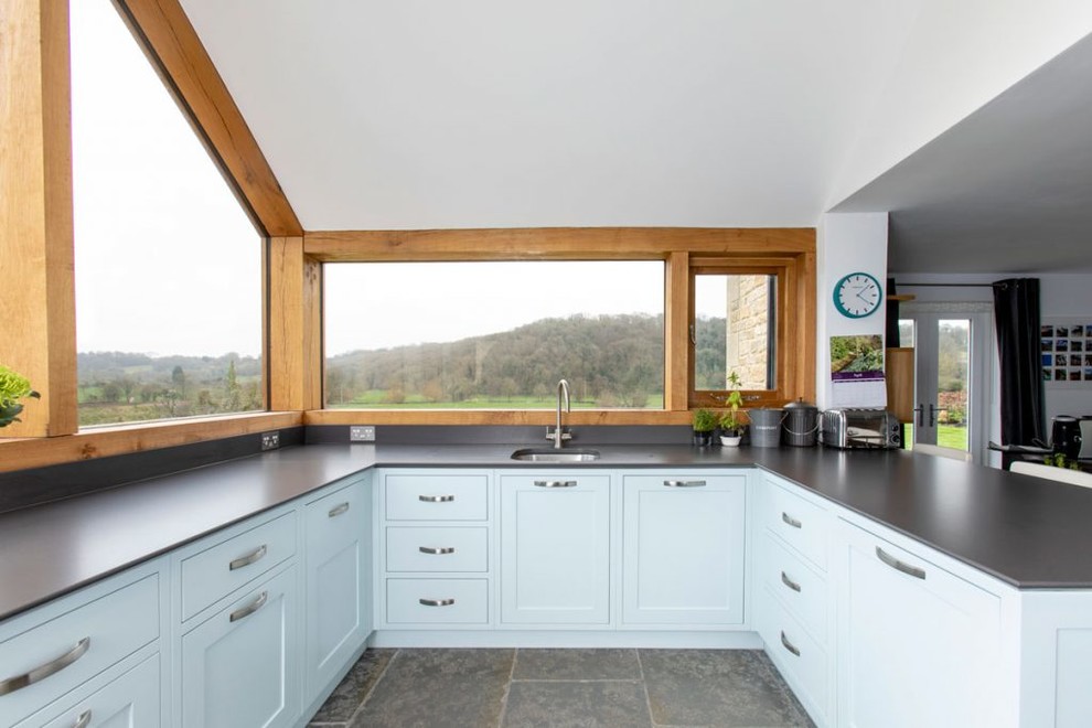 Inspiration for a medium sized traditional u-shaped open plan kitchen in Wiltshire with an integrated sink, shaker cabinets, blue cabinets, blue splashback, stainless steel appliances, no island and grey floors.
