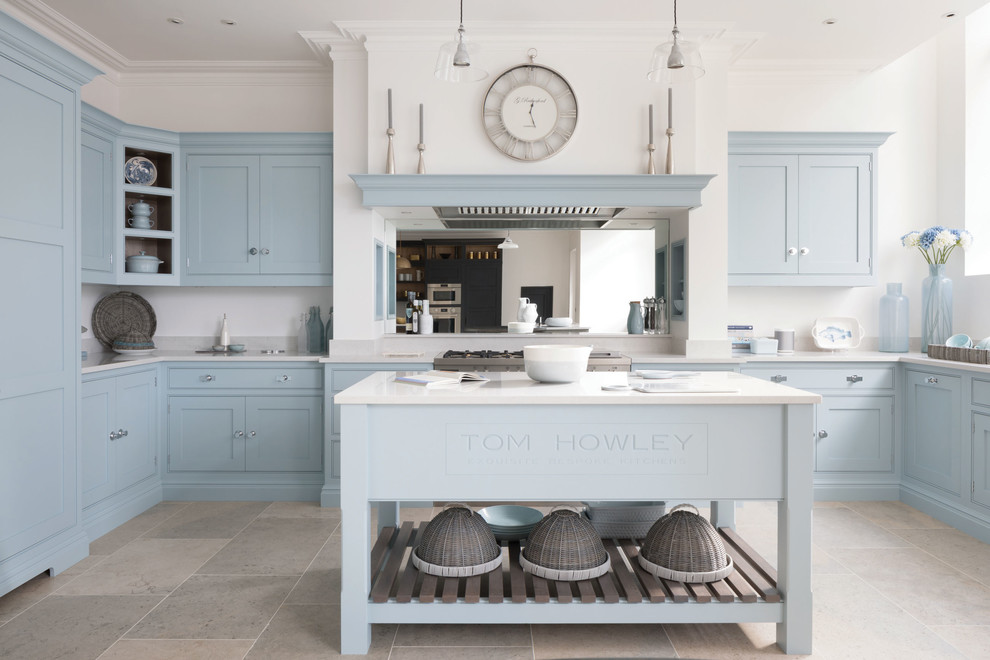 Large classic u-shaped enclosed kitchen in Edinburgh with an integrated sink, shaker cabinets, blue cabinets, engineered stone countertops, white splashback, stainless steel appliances, an island and white worktops.