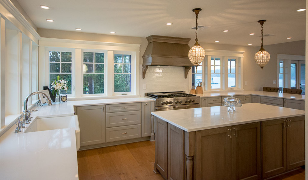 Inspiration for a large coastal u-shaped light wood floor open concept kitchen remodel in Portland with a farmhouse sink, recessed-panel cabinets, gray cabinets, quartz countertops, white backsplash, window backsplash, stainless steel appliances and an island