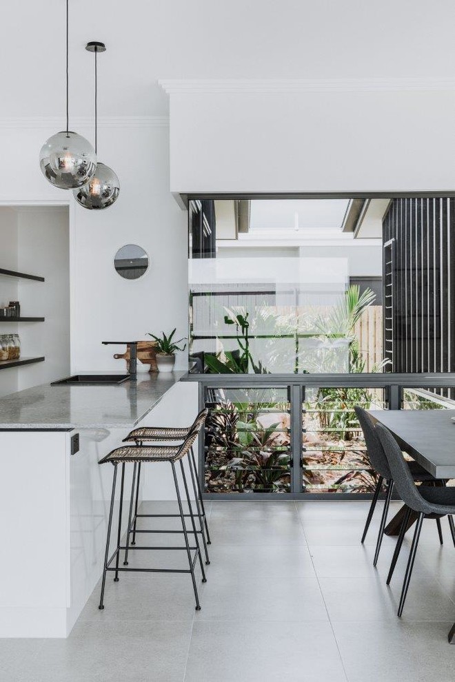 Inspiration for a medium sized contemporary galley kitchen/diner in Townsville with a submerged sink, flat-panel cabinets, grey cabinets, engineered stone countertops, metallic splashback, mirror splashback, stainless steel appliances, porcelain flooring, an island, beige floors and grey worktops.