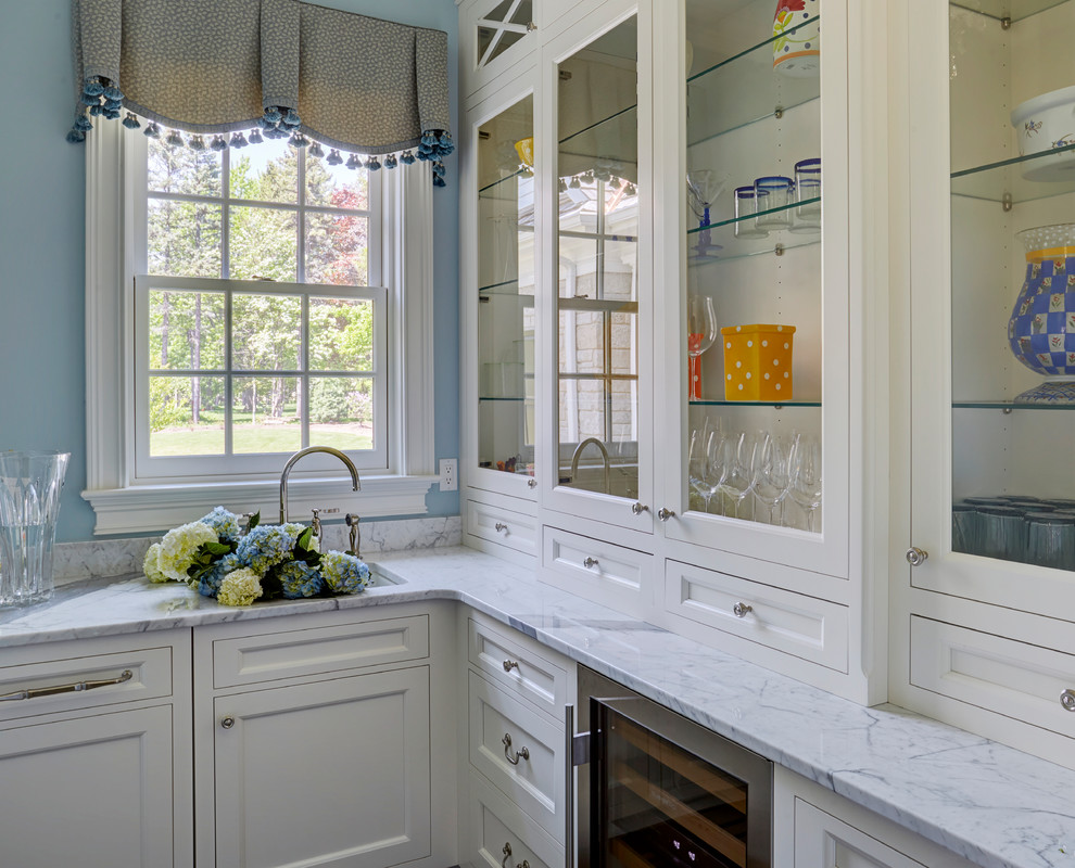 Foto på ett litet vintage vit kök, med en undermonterad diskho, luckor med infälld panel, vita skåp, marmorbänkskiva, vitt stänkskydd, stänkskydd i marmor, rostfria vitvaror, mörkt trägolv och brunt golv