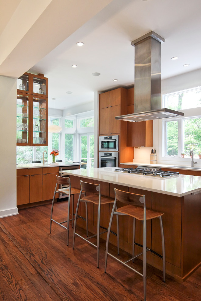 Foto på ett funkis vit kök, med släta luckor, skåp i mellenmörkt trä, vitt stänkskydd, mörkt trägolv, en köksö, en undermonterad diskho, bänkskiva i kvarts och rostfria vitvaror