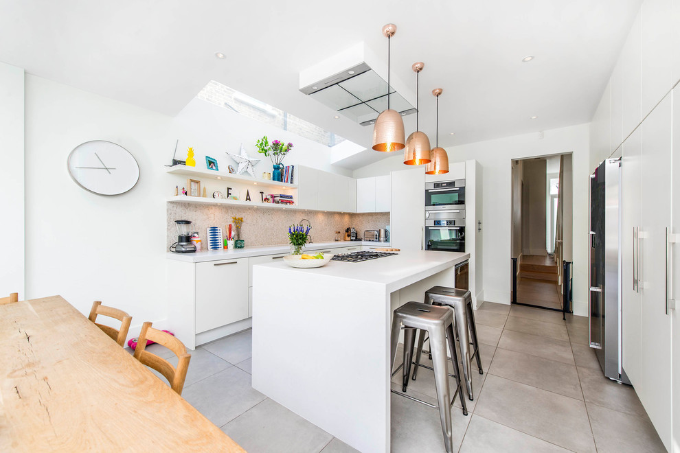 Moderne Wohnküche in U-Form mit flächenbündigen Schrankfronten, weißen Schränken, Küchenrückwand in Braun, Rückwand aus Mosaikfliesen, Küchengeräten aus Edelstahl, Kücheninsel und grauem Boden in London