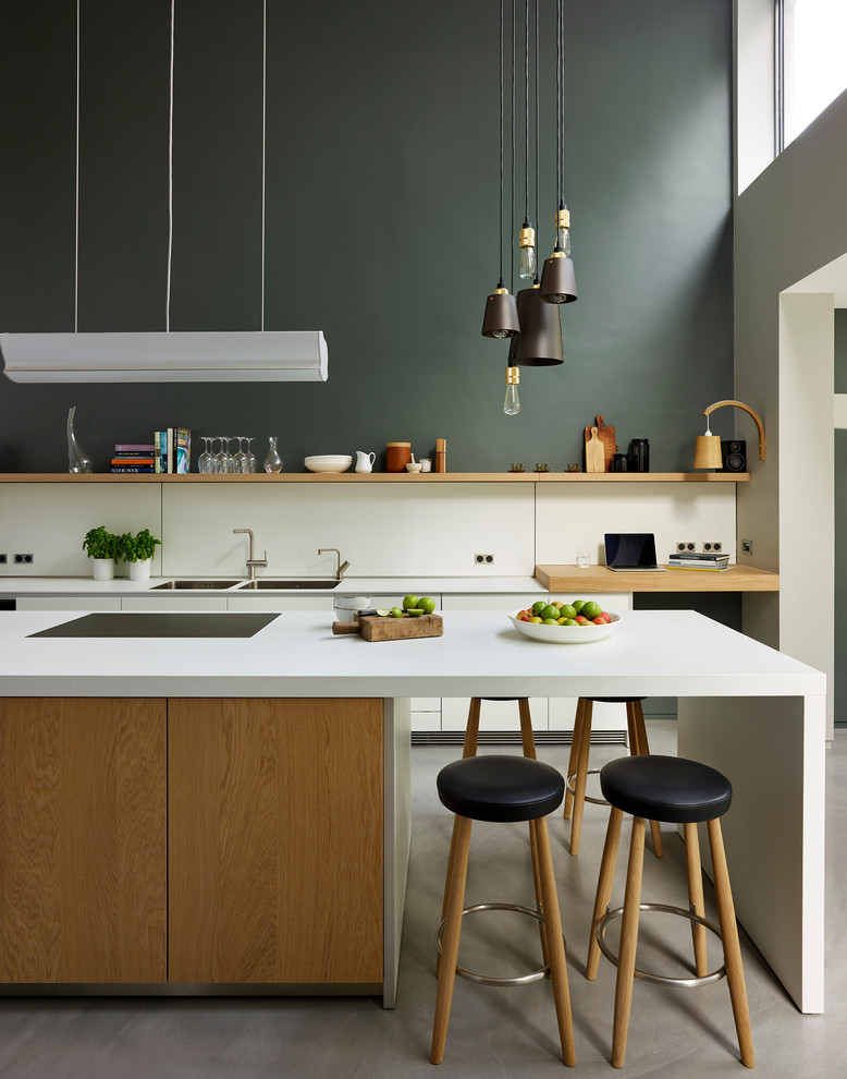 Inspiration pour une cuisine bicolore design en bois clair avec un évier 2 bacs, un placard à porte plane, une crédence blanche, sol en béton ciré et îlot.