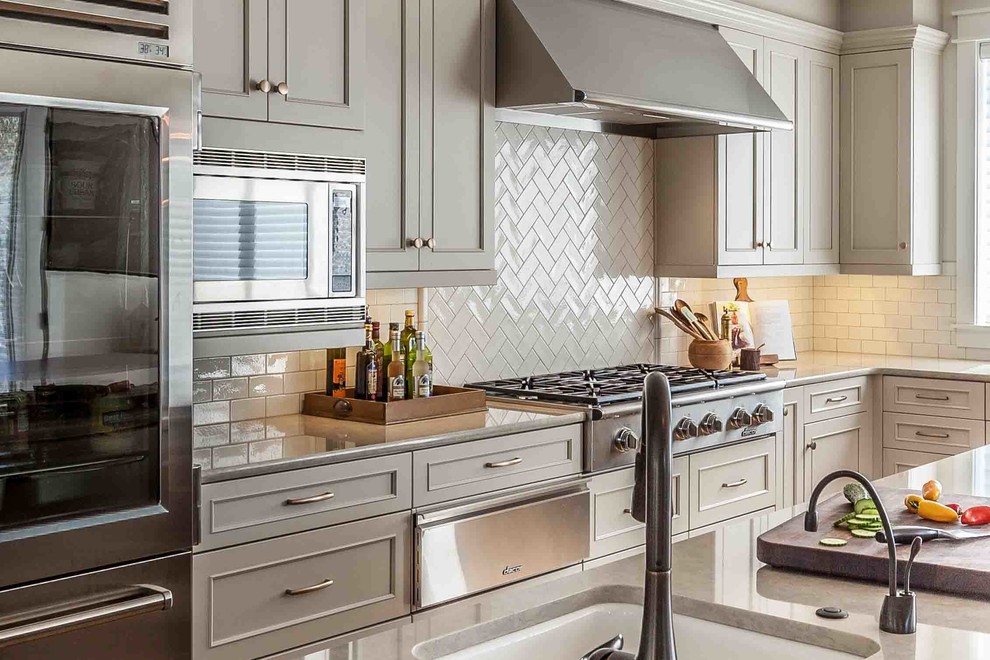 Eat-in kitchen - huge traditional l-shaped medium tone wood floor eat-in kitchen idea in Seattle with an undermount sink, recessed-panel cabinets, gray cabinets, quartz countertops, white backsplash, ceramic backsplash, stainless steel appliances and an island