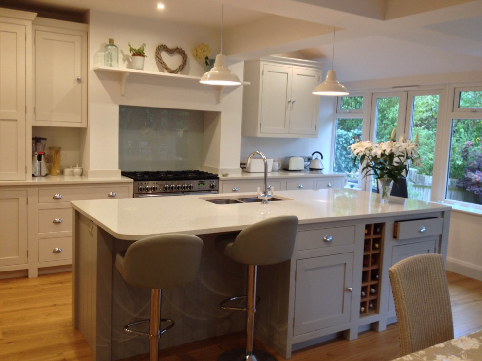Foto di una grande cucina chic con lavello da incasso, ante a filo, ante grigie, pavimento in compensato e top bianco