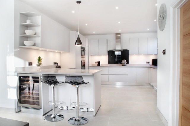 Light grey handle-less kitchen with black splash back ...