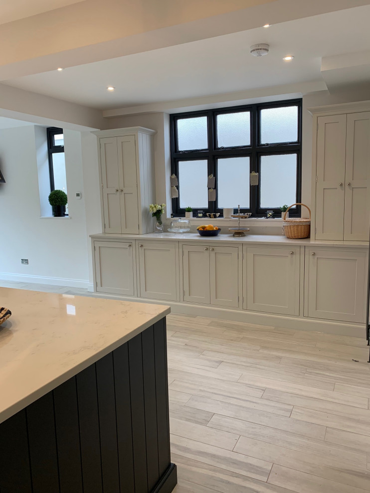 This is an example of a medium sized traditional l-shaped kitchen in Surrey with beaded cabinets, blue cabinets, quartz worktops, metallic splashback, an island and white worktops.
