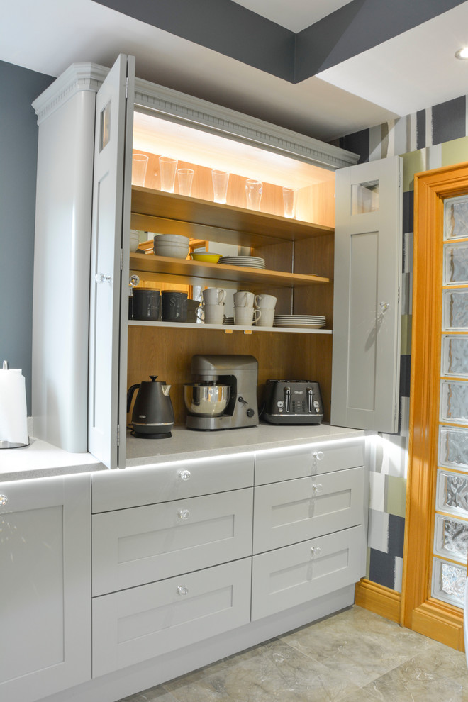Modelo de cocina clásica renovada abierta con fregadero sobremueble, armarios estilo shaker, puertas de armario grises, encimera de cuarcita y península