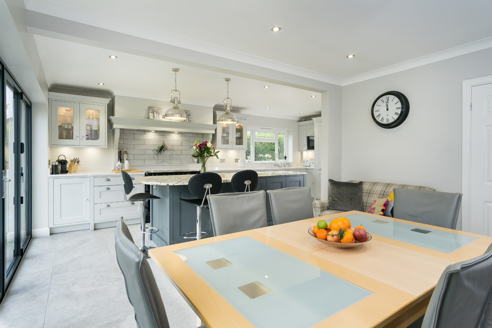 This is an example of a large traditional grey and white single-wall kitchen/diner in Other with a built-in sink, shaker cabinets, grey cabinets, engineered stone countertops, white splashback, ceramic splashback, black appliances, ceramic flooring, an island, grey floors and white worktops.