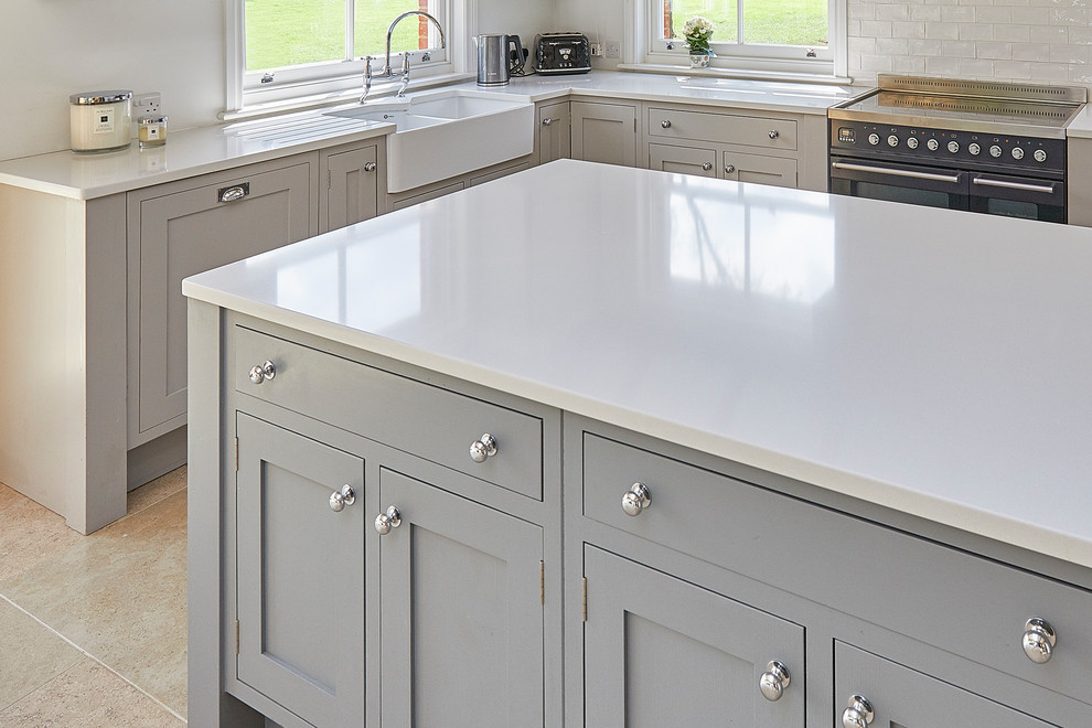 Inspiration for a large classic u-shaped kitchen/diner in Surrey with a double-bowl sink, shaker cabinets, grey cabinets, composite countertops, white splashback, porcelain splashback, stainless steel appliances, travertine flooring, an island, beige floors and white worktops.