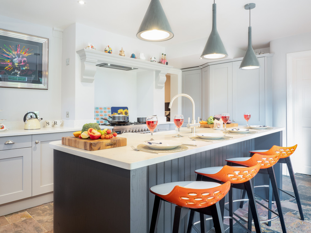 Immagine di un cucina con isola centrale tradizionale di medie dimensioni con ante in stile shaker, ante grigie, elettrodomestici in acciaio inossidabile, pavimento multicolore e top bianco