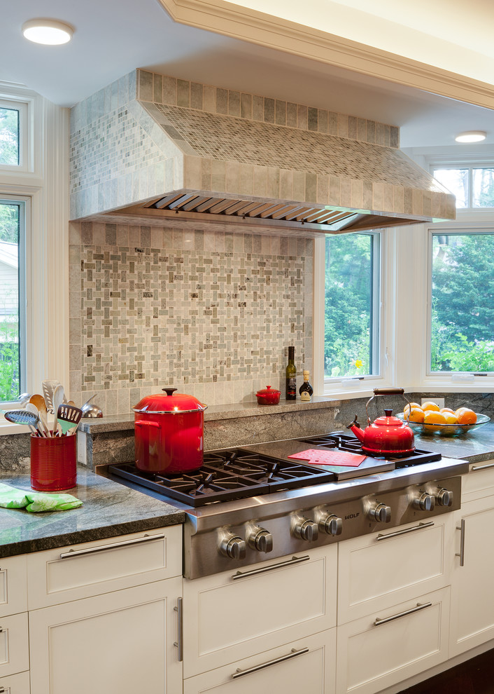 Klassisk inredning av ett stort kök, med en undermonterad diskho, skåp i shakerstil, vita skåp, granitbänkskiva, grönt stänkskydd, stänkskydd i stenkakel, rostfria vitvaror och mellanmörkt trägolv