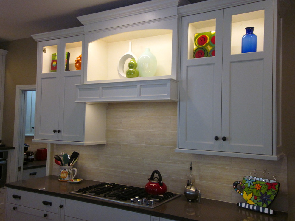 Inredning av ett klassiskt kök med öppen planlösning, med en undermonterad diskho, luckor med infälld panel, vita skåp, bänkskiva i kvarts, beige stänkskydd, stänkskydd i porslinskakel, rostfria vitvaror, ljust trägolv och en köksö