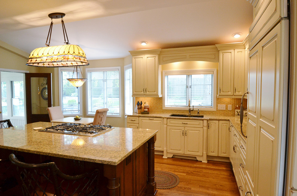 Example of a large transitional l-shaped medium tone wood floor eat-in kitchen design in Columbus with an undermount sink, raised-panel cabinets, beige cabinets, granite countertops, beige backsplash, paneled appliances and an island