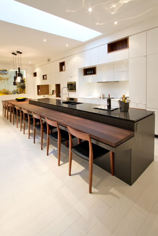 Foto di una grande cucina minimalista con lavello sottopiano, ante lisce, ante bianche, paraspruzzi bianco, elettrodomestici in acciaio inossidabile, parquet chiaro e top grigio