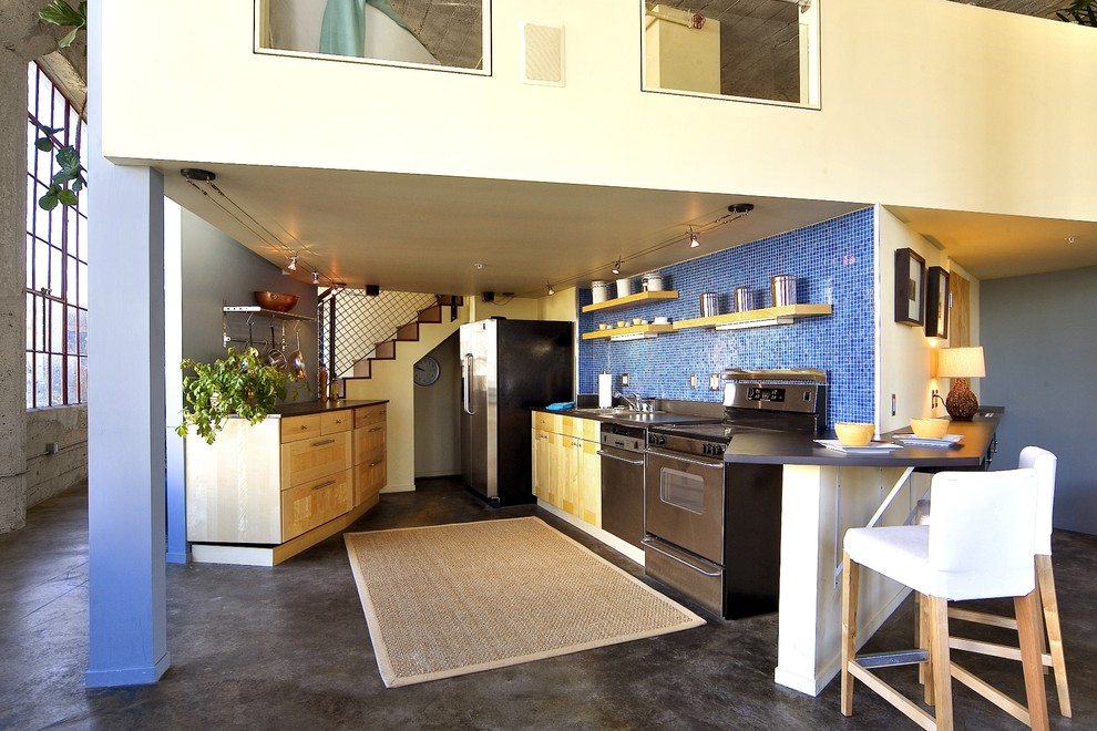 Imagen de cocina industrial con puertas de armario de madera clara, salpicadero azul, salpicadero con mosaicos de azulejos y electrodomésticos de acero inoxidable