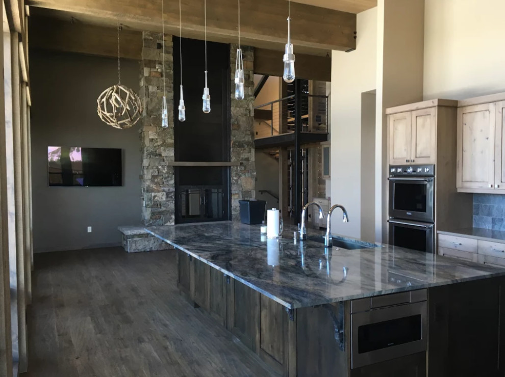 Open concept kitchen - mid-sized rustic single-wall dark wood floor and brown floor open concept kitchen idea in Other with an undermount sink, shaker cabinets, medium tone wood cabinets, granite countertops, gray backsplash, slate backsplash, stainless steel appliances and an island