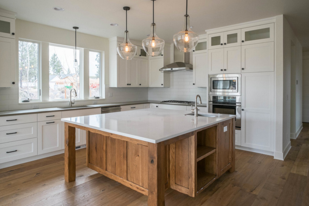 Eat-in kitchen - large transitional l-shaped medium tone wood floor eat-in kitchen idea in Portland with an integrated sink, recessed-panel cabinets, white cabinets, quartzite countertops, white backsplash, subway tile backsplash, stainless steel appliances and an island
