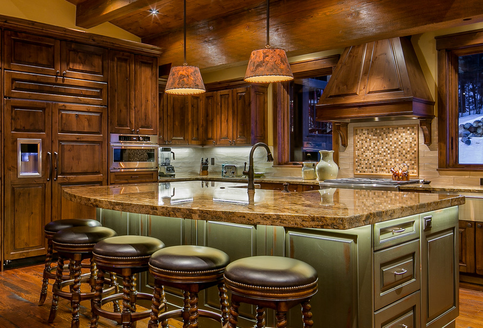 Rustikale Küche in L-Form mit profilierten Schrankfronten, dunklen Holzschränken, bunter Rückwand, Rückwand aus Mosaikfliesen, Elektrogeräten mit Frontblende, dunklem Holzboden und Kücheninsel