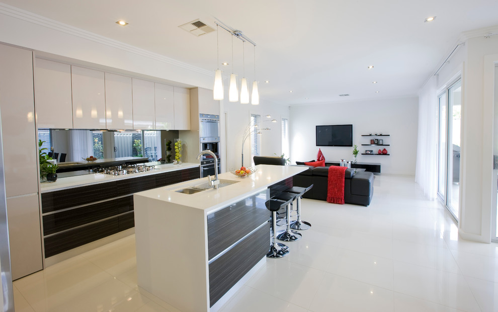 Photo of a large contemporary l-shaped kitchen/diner in Adelaide with a double-bowl sink, dark wood cabinets, engineered stone countertops, mirror splashback, stainless steel appliances, porcelain flooring and an island.