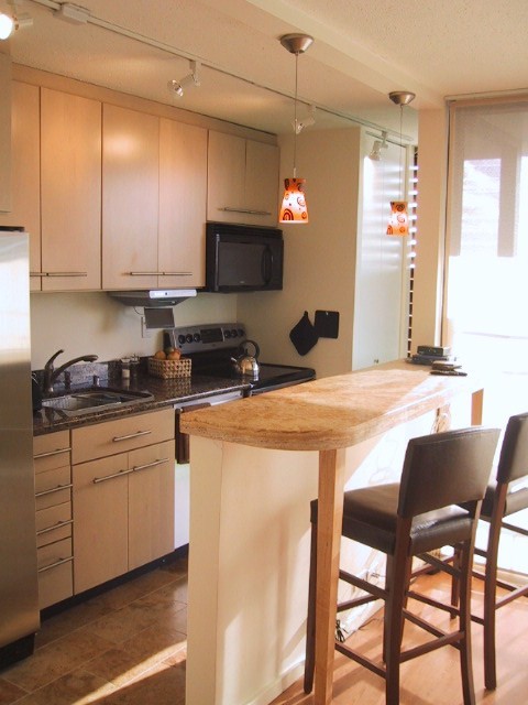 This is an example of a medium sized contemporary galley open plan kitchen in Hawaii with a built-in sink, flat-panel cabinets, light wood cabinets, limestone worktops, stainless steel appliances, limestone flooring and no island.