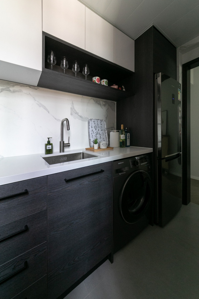 Bild på ett avskilt, litet funkis vit vitt l-kök, med en nedsänkt diskho, släta luckor, svarta skåp, bänkskiva i kalksten, vitt stänkskydd, stänkskydd i marmor, svarta vitvaror, klinkergolv i keramik och grått golv