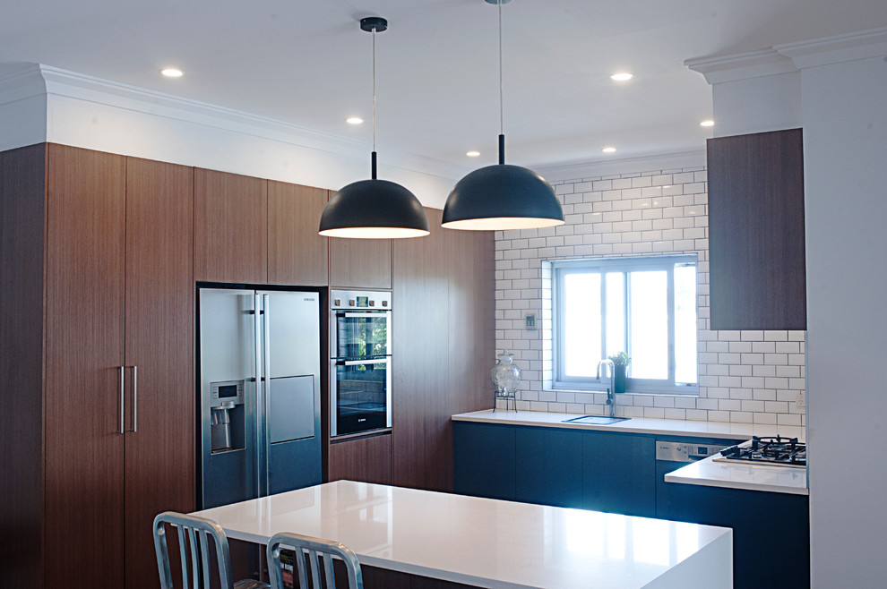 Example of a large minimalist u-shaped open concept kitchen design in Sydney with a drop-in sink, recessed-panel cabinets, black cabinets, white backsplash, subway tile backsplash, stainless steel appliances and an island