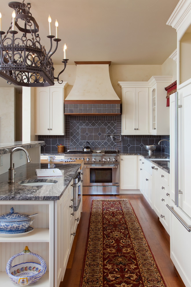 他の地域にあるトラディショナルスタイルのおしゃれなキッチン (シングルシンク、落し込みパネル扉のキャビネット、白いキャビネット、グレーのキッチンパネル、パネルと同色の調理設備、無垢フローリング) の写真