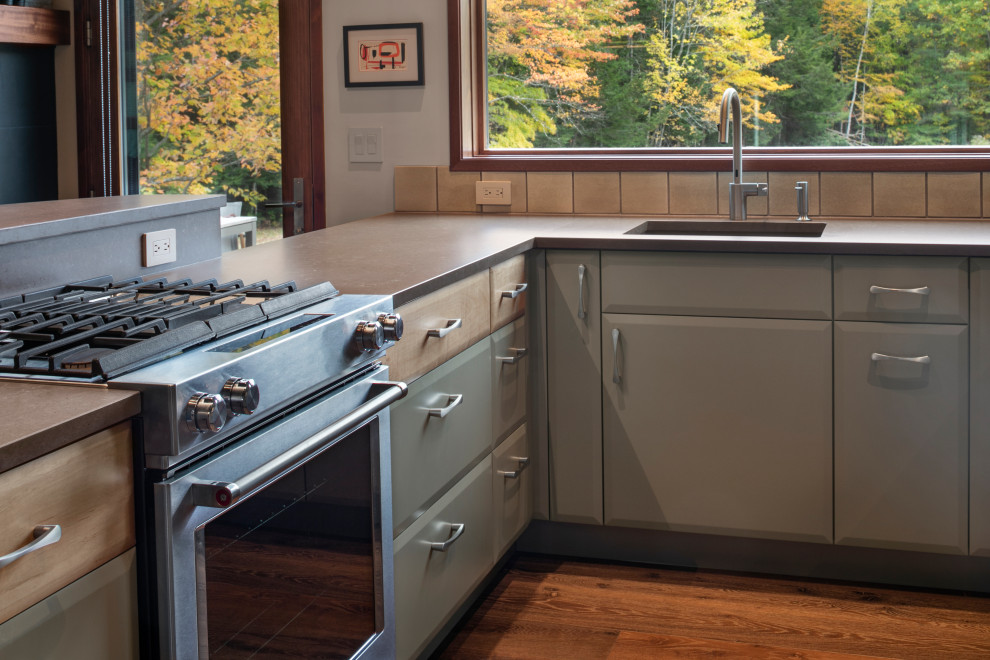 Inspiration for a medium sized retro u-shaped open plan kitchen in Manchester with a submerged sink, flat-panel cabinets, light wood cabinets, beige splashback, stainless steel appliances, medium hardwood flooring, a breakfast bar and grey worktops.