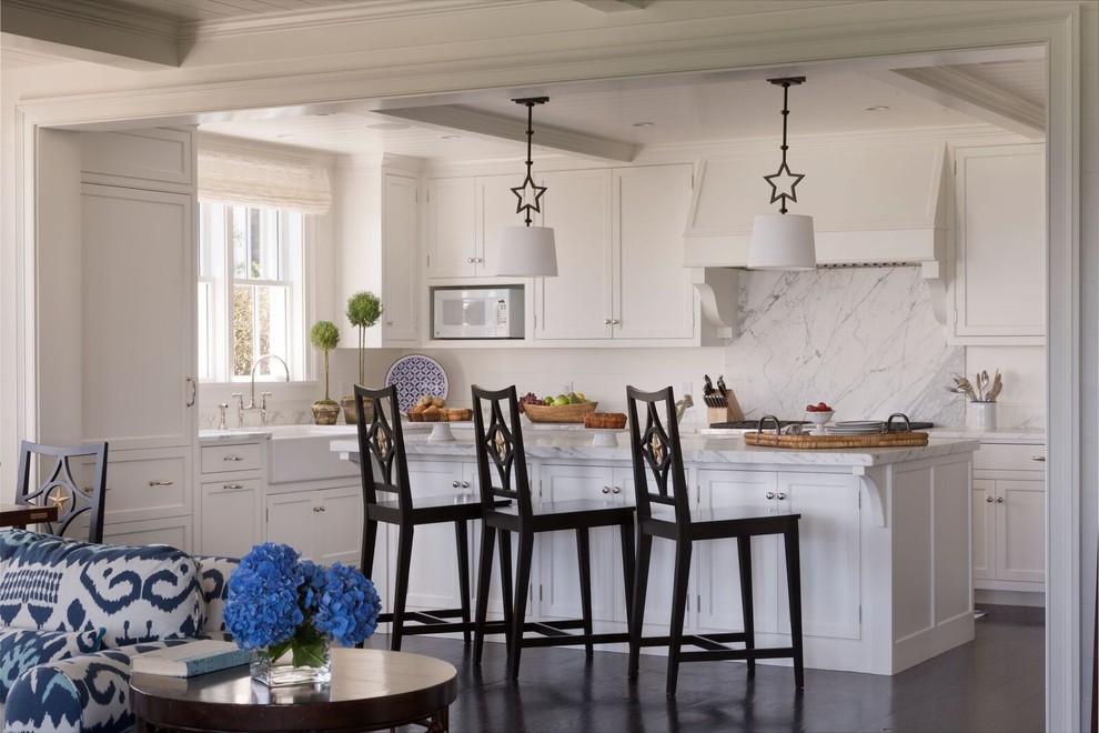 Photo of a large beach style u-shaped kitchen/diner in Boston with a submerged sink, recessed-panel cabinets, white cabinets, marble worktops, white splashback, integrated appliances, dark hardwood flooring and an island.