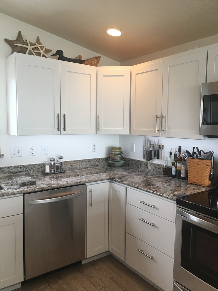 Medium sized coastal u-shaped enclosed kitchen in Portland with a submerged sink, shaker cabinets, white cabinets, granite worktops, stainless steel appliances, vinyl flooring and a breakfast bar.