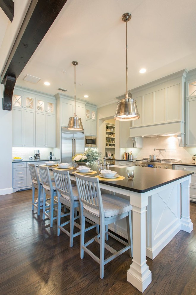 Example of a classic l-shaped dark wood floor kitchen design in Dallas with a farmhouse sink, shaker cabinets, gray cabinets, white backsplash, stainless steel appliances and an island
