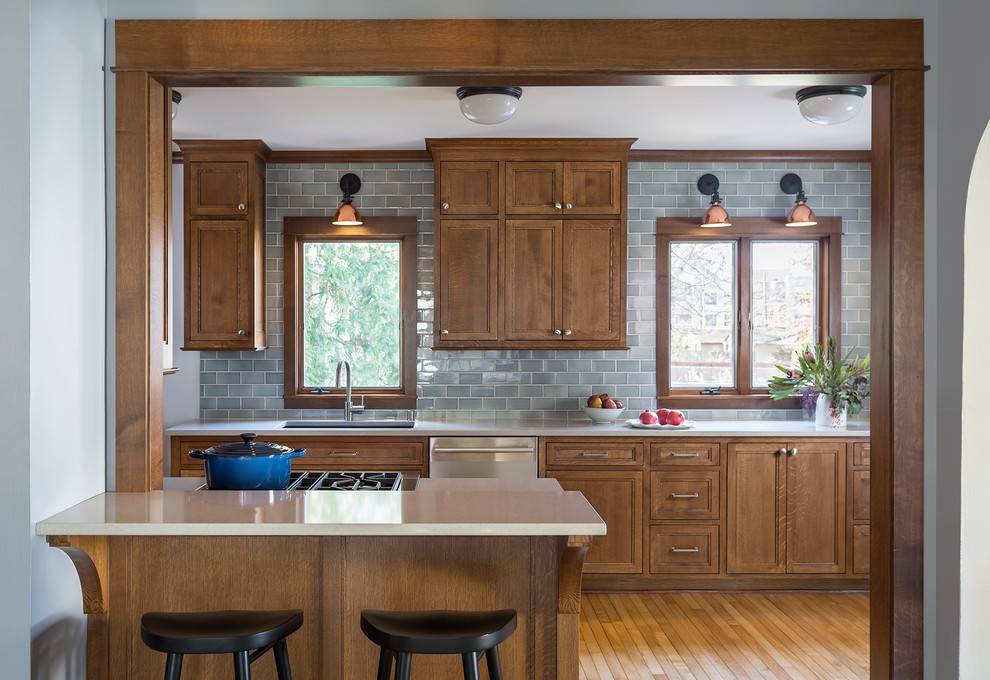 ミネアポリスにある中くらいなトラディショナルスタイルのおしゃれなキッチン (アンダーカウンターシンク、中間色木目調キャビネット、クオーツストーンカウンター、青いキッチンパネル、セラミックタイルのキッチンパネル、シルバーの調理設備、茶色い床、落し込みパネル扉のキャビネット、無垢フローリング) の写真