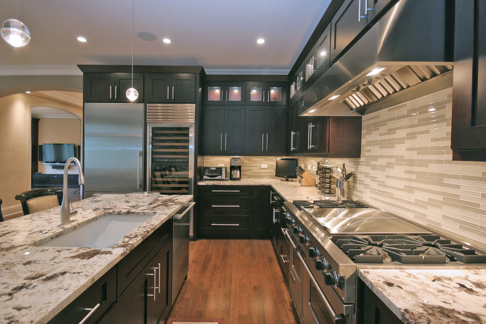 Example of a mid-sized classic u-shaped medium tone wood floor eat-in kitchen design in Chicago with an undermount sink, shaker cabinets, dark wood cabinets, granite countertops, beige backsplash, matchstick tile backsplash, stainless steel appliances and an island