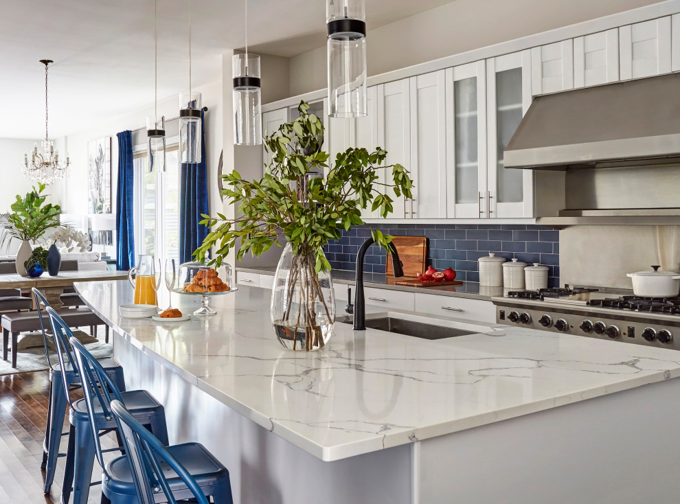 Foto på ett mycket stort vintage vit kök, med en undermonterad diskho, skåp i shakerstil, vita skåp, bänkskiva i kvarts, blått stänkskydd, stänkskydd i keramik, rostfria vitvaror, mellanmörkt trägolv, en köksö och brunt golv