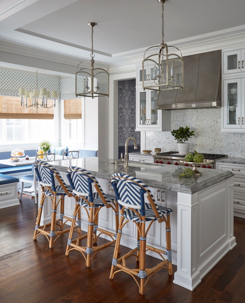 Inredning av ett klassiskt grå grått kök, med en undermonterad diskho, luckor med upphöjd panel, vita skåp, flerfärgad stänkskydd, rostfria vitvaror, mellanmörkt trägolv, en köksö och brunt golv