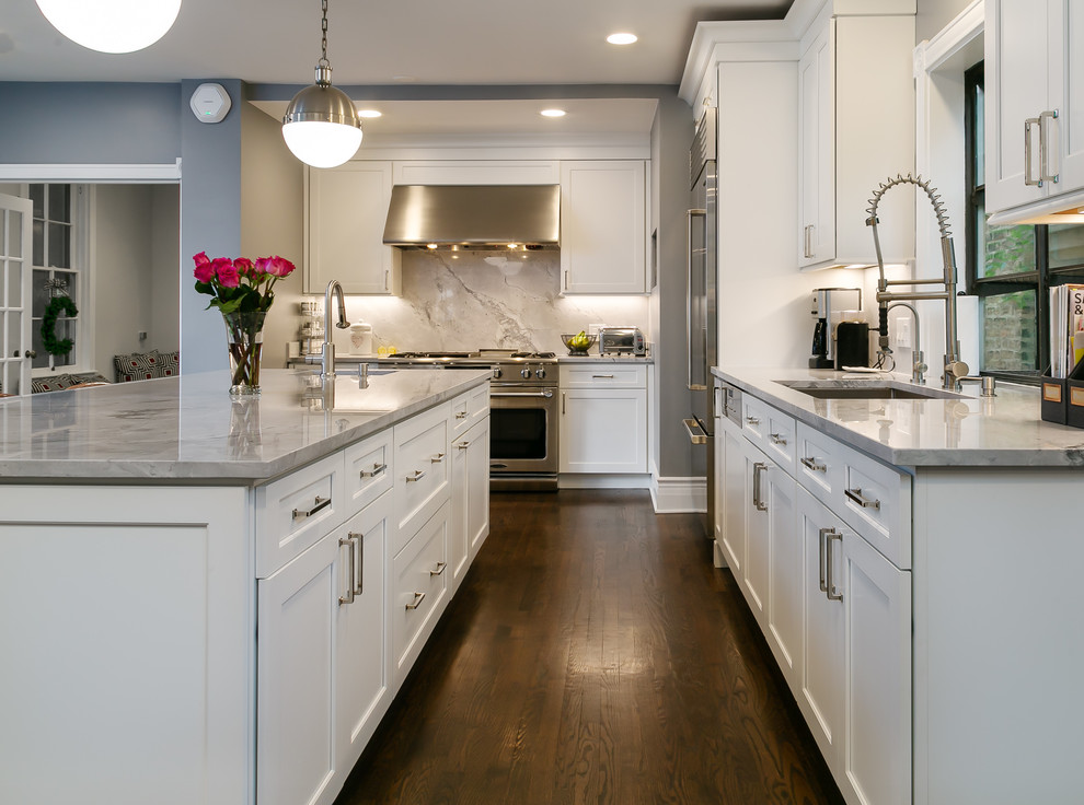 Design ideas for a large traditional l-shaped open plan kitchen in Chicago with shaker cabinets, white cabinets, granite worktops, grey splashback, stone slab splashback, stainless steel appliances, an island, grey worktops, a submerged sink, dark hardwood flooring and brown floors.
