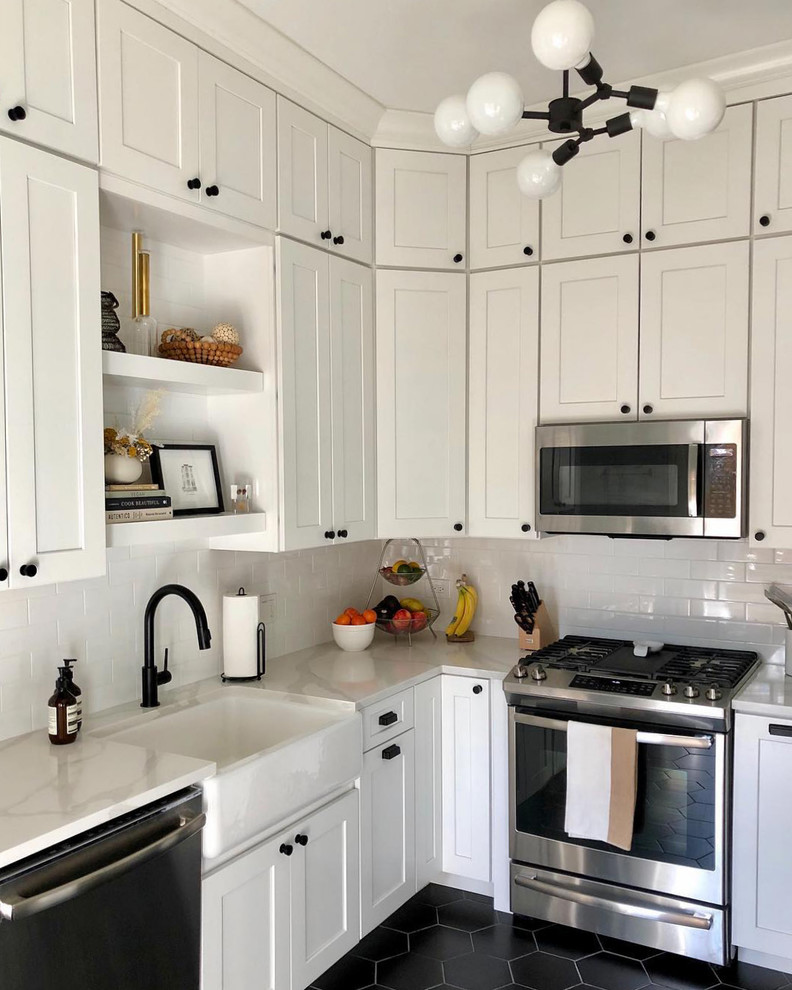 Example of a mid-sized farmhouse u-shaped porcelain tile and black floor enclosed kitchen design in Chicago with a farmhouse sink, shaker cabinets, white cabinets, quartz countertops, white backsplash, ceramic backsplash, stainless steel appliances, no island and white countertops