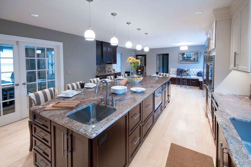 Huge transitional l-shaped light wood floor open concept kitchen photo in Providence with an island, shaker cabinets, white cabinets, granite countertops, white backsplash, stone tile backsplash, stainless steel appliances and an undermount sink