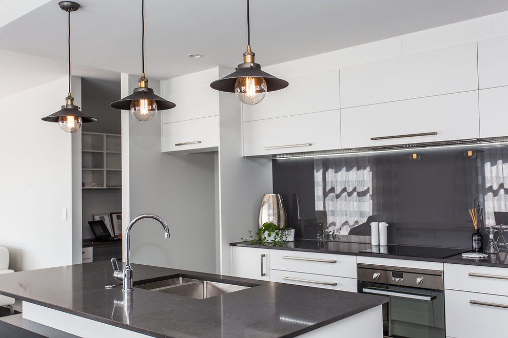 Modern inredning av ett mellanstort kök, med vita skåp, granitbänkskiva och en köksö