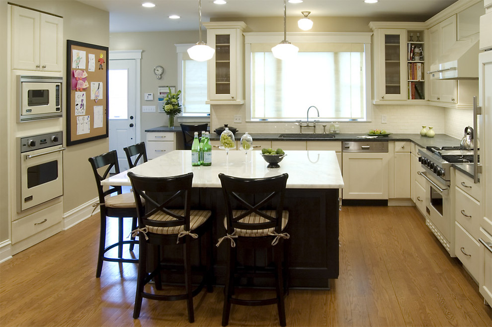 Kitchen - traditional l-shaped kitchen idea in Chicago with glass-front cabinets, white appliances, white cabinets, soapstone countertops and white backsplash
