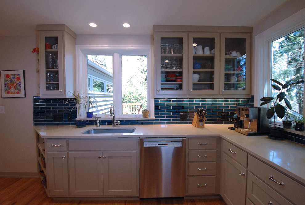 Exempel på ett avskilt, litet klassiskt parallellkök, med en undermonterad diskho, luckor med infälld panel, beige skåp, bänkskiva i kvarts, blått stänkskydd, stänkskydd i keramik, rostfria vitvaror, mellanmörkt trägolv och en halv köksö