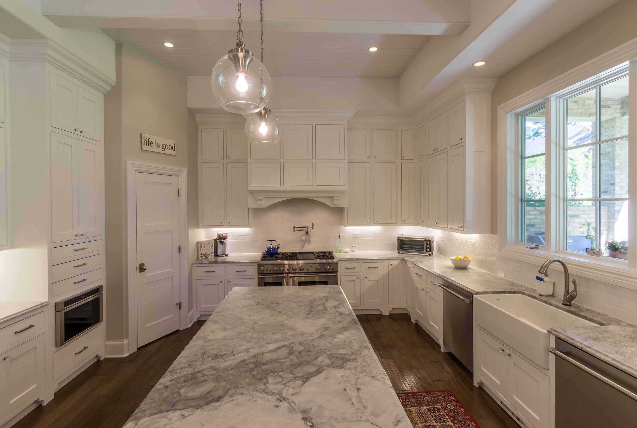 Large elegant galley medium tone wood floor, brown floor and coffered ceiling eat-in kitchen photo in Chicago with a farmhouse sink, recessed-panel cabinets, white cabinets, marble countertops, white backsplash, subway tile backsplash, stainless steel appliances, an island and gray countertops