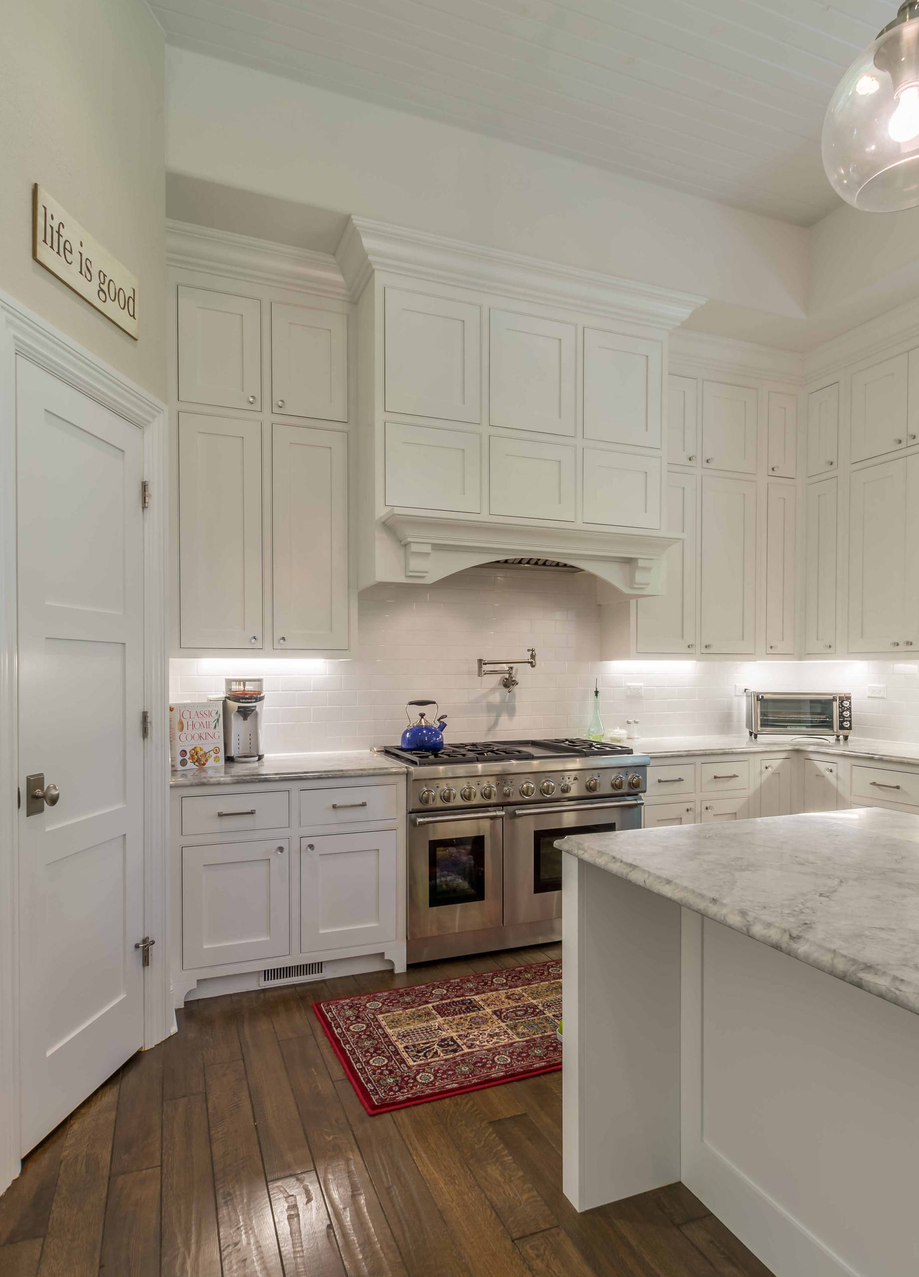 Large transitional galley medium tone wood floor, brown floor and coffered ceiling eat-in kitchen photo in Chicago with a farmhouse sink, recessed-panel cabinets, white cabinets, marble countertops, white backsplash, subway tile backsplash, stainless steel appliances, an island and gray countertops